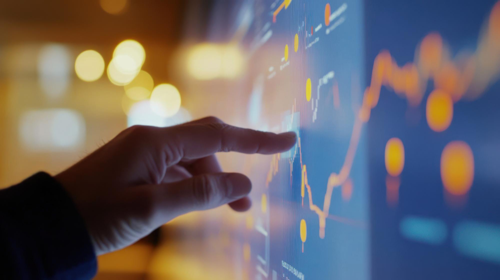 A hand interacts with a digital screen displaying financial data and graphs